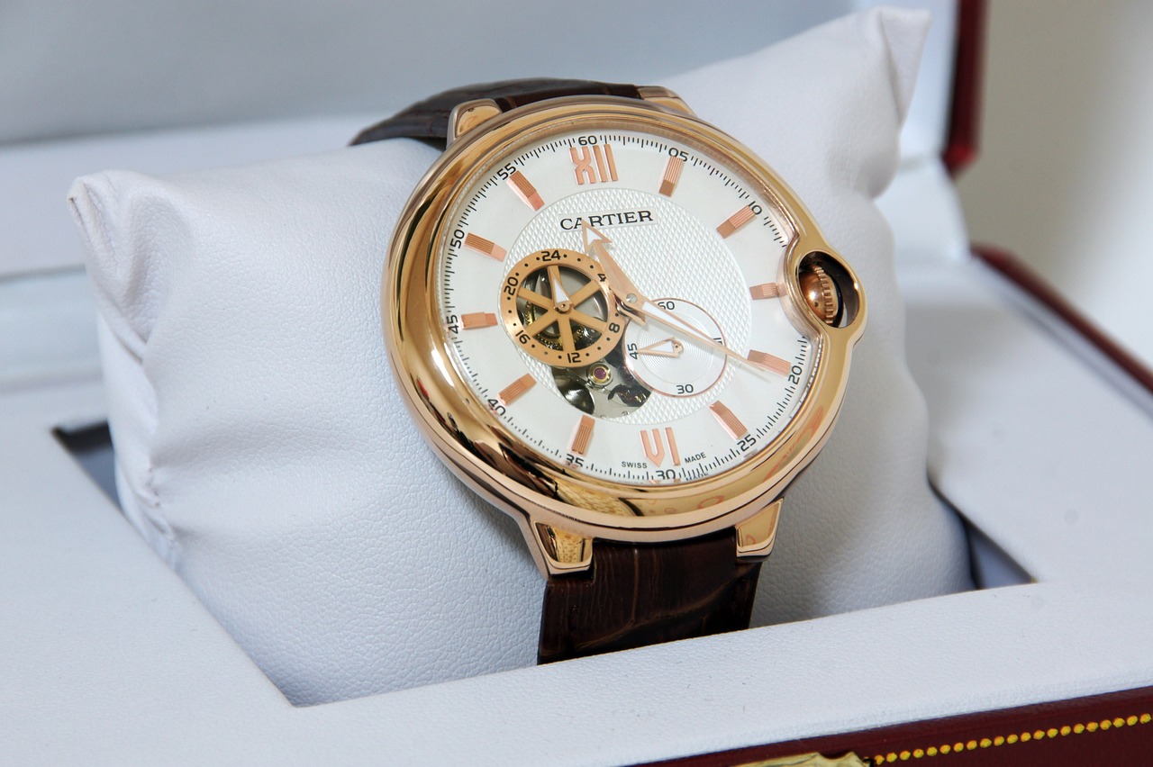 Cartier roségouden horloge met open balans, bruine leren band en witte wijzerplaat op een kussentje